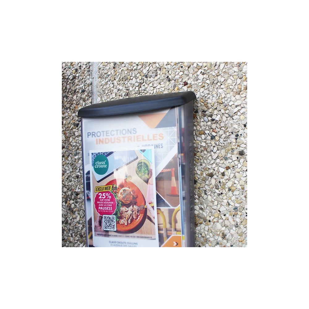Photo de mise en situation avec le porte brochure accroché sur un mur en extérieur.