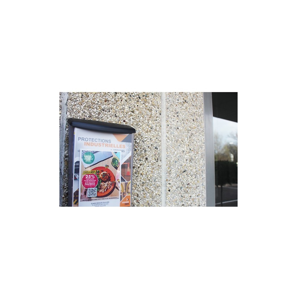 Photo de mise en situation avec le porte brochure accroché sur un mur en extérieur.